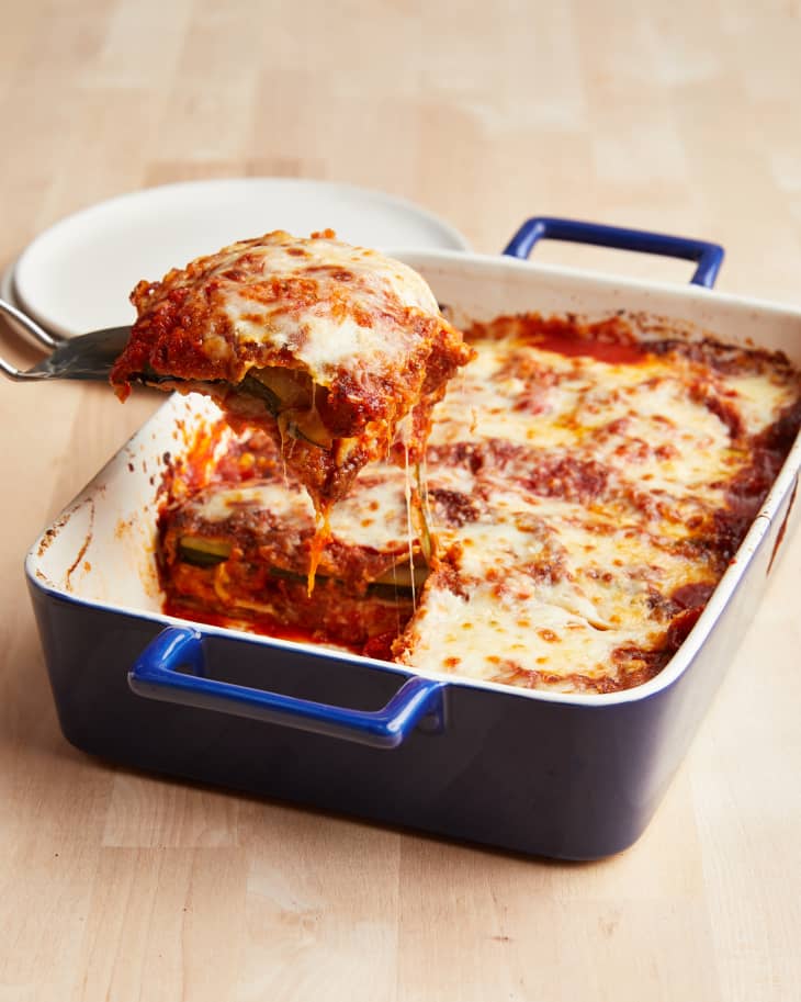 Zucchini parmesan in blue baking dish with one square piece being sliced out with lasagna server