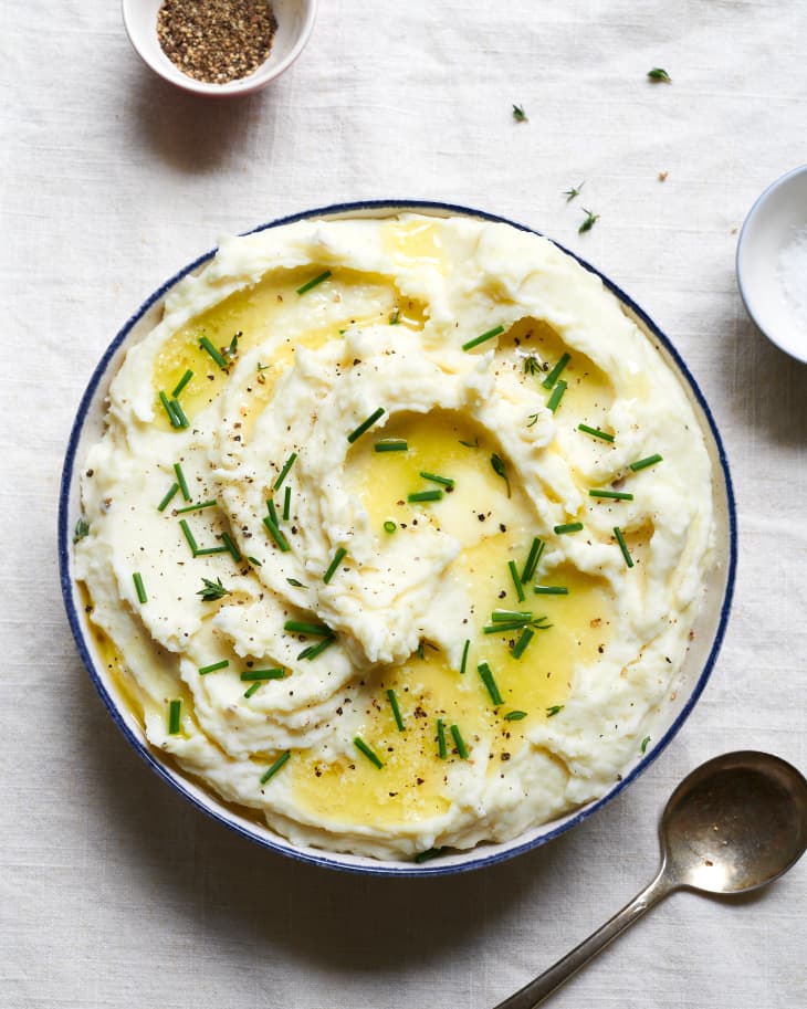 Cream cheese mashed potatoes in bowl with butter and chives.