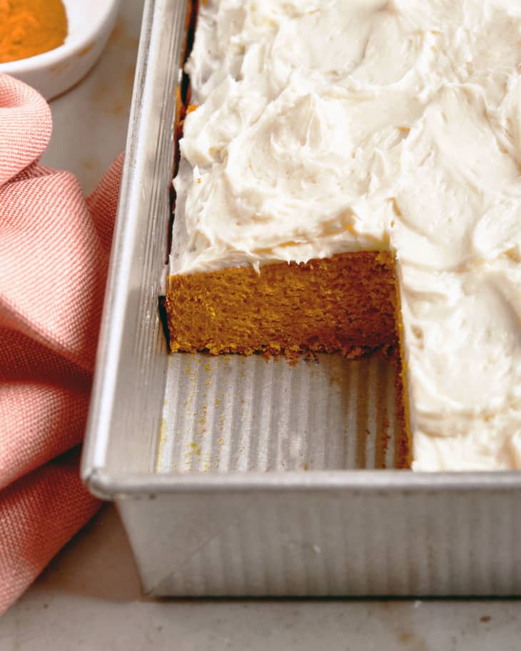 Pumpkin sheet cake in baking tin with slice cut out.