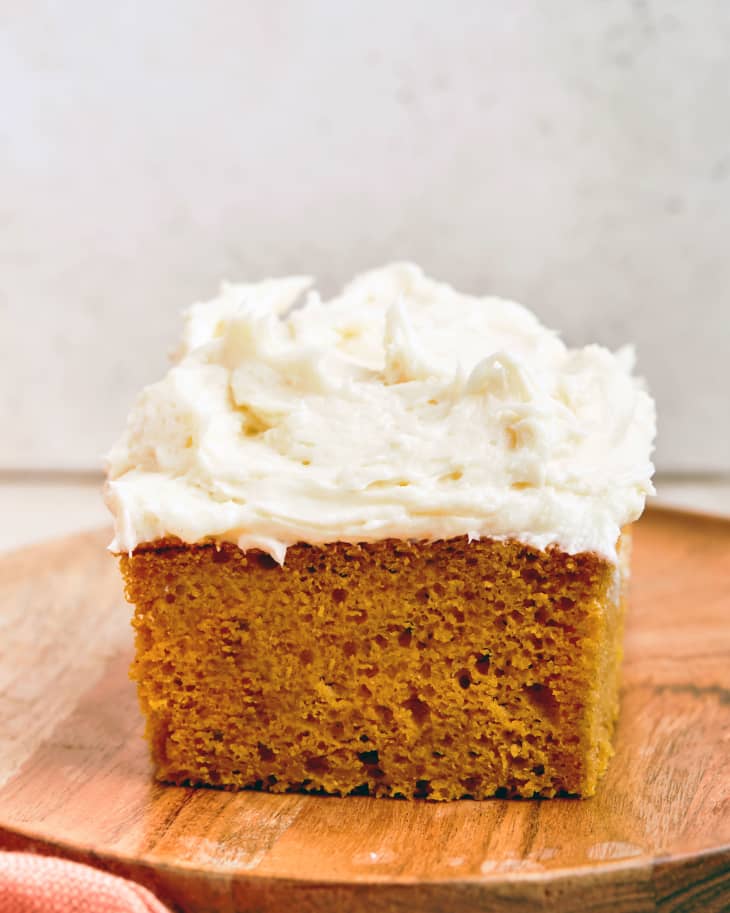 Image 3: Slice of pumpkin sheet cake on wooden board.