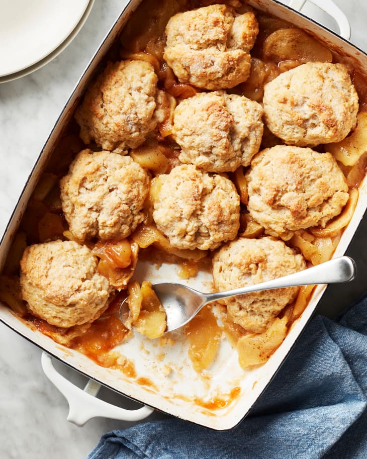 Easy apple cobbler in baking dish with serving missing and spoon inside.