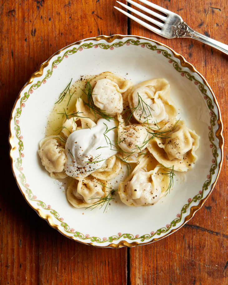 A bowl of pelmenis sit on a wood table.