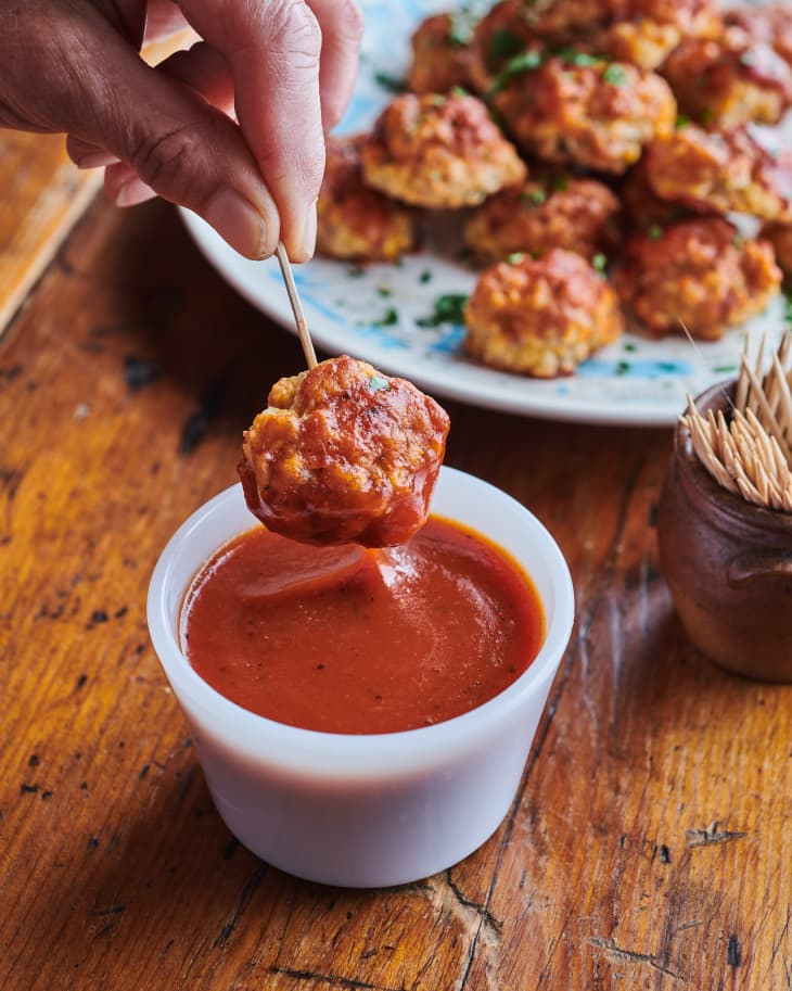 Someone dipping sausage ball into barbecue sauce.
