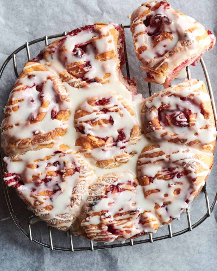 Cranberry vanilla morning buns on cooling rack with one bun torn off to the side.