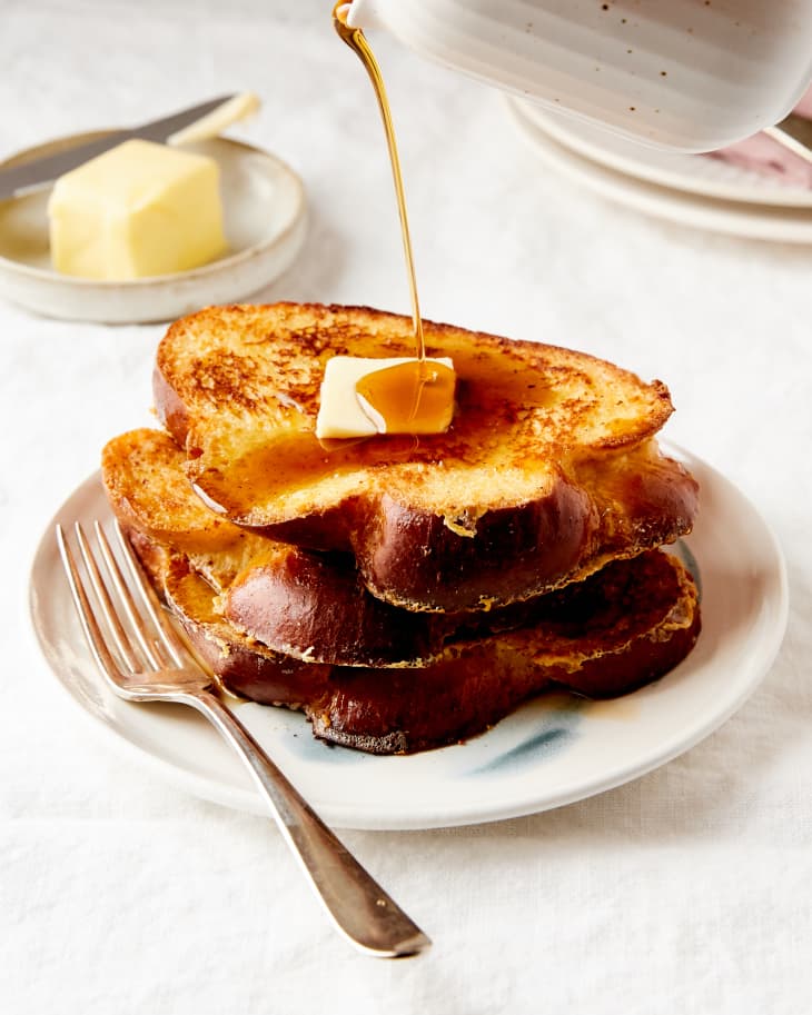 Maple syrup is poured over a stack of french toast.
