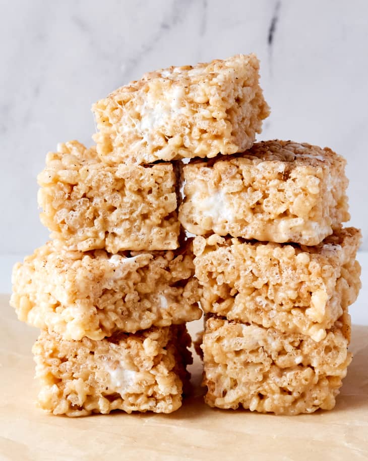 Eggnog rice krispies are stacked on parchment paper.