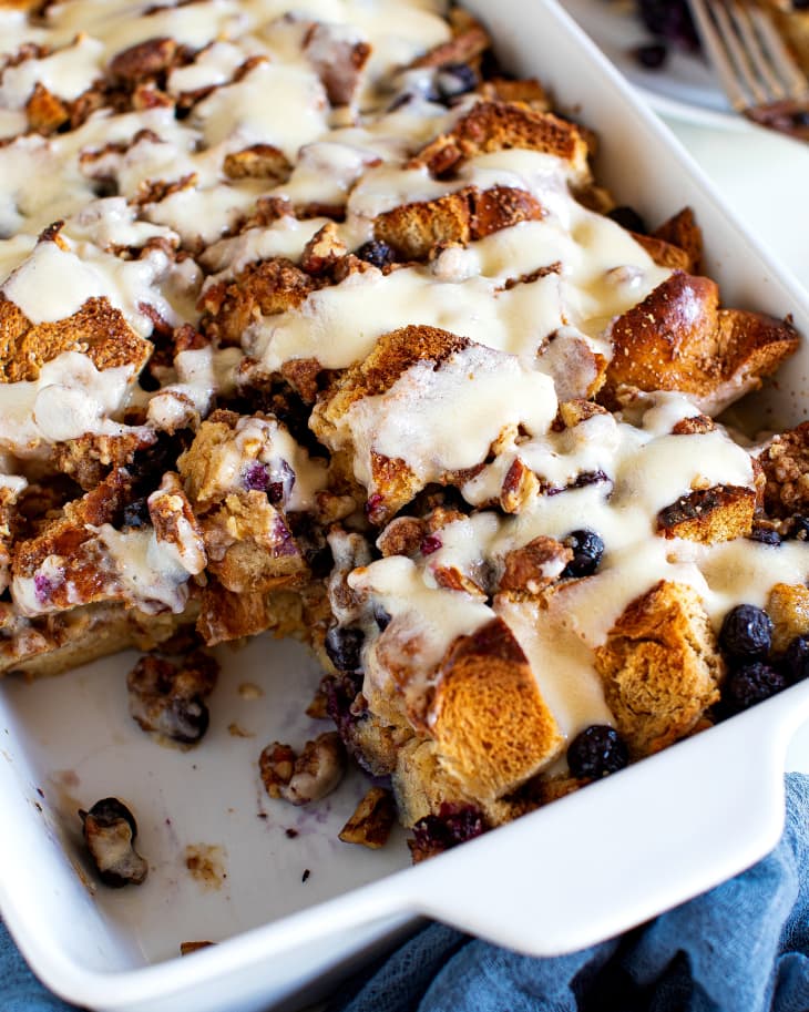 Slight overhead photo of Overnight Blueberry Cheesecake French Toast Casserole in a white casserole dish with a blue napkin