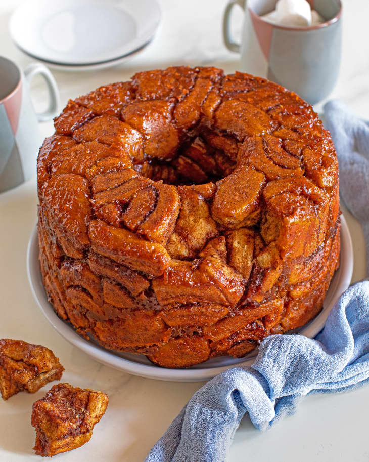 pumpkin chai monkey bread sits on a plate near a light blue napkin with two pieces pulled off and on the side