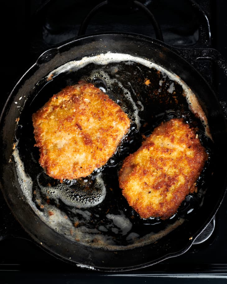 two pork chops are in a deep fryer