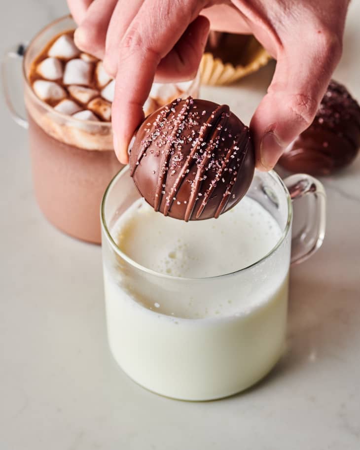 someone is dropping the chocolate bomb into a glass of milk