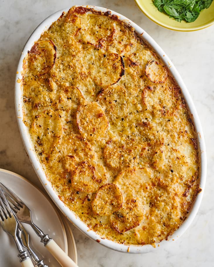 ranch potato gratin sits on a table next to cutlery and plates