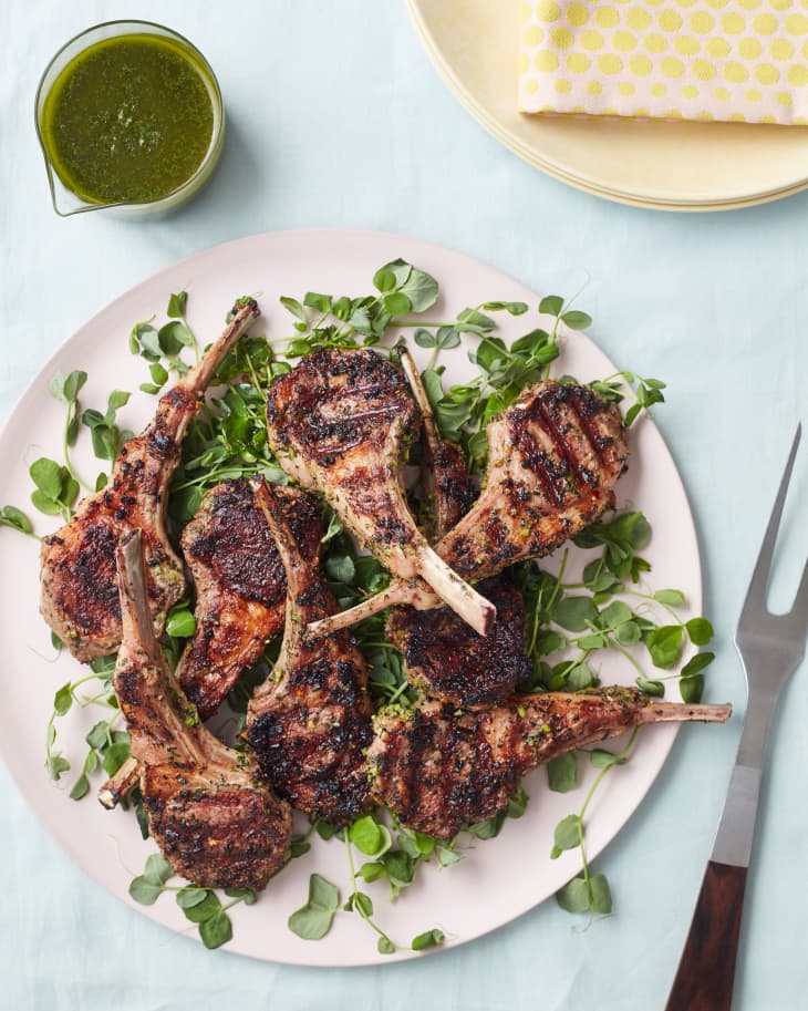 grilled lambchops garnished on a plate next to sauce and cutlery