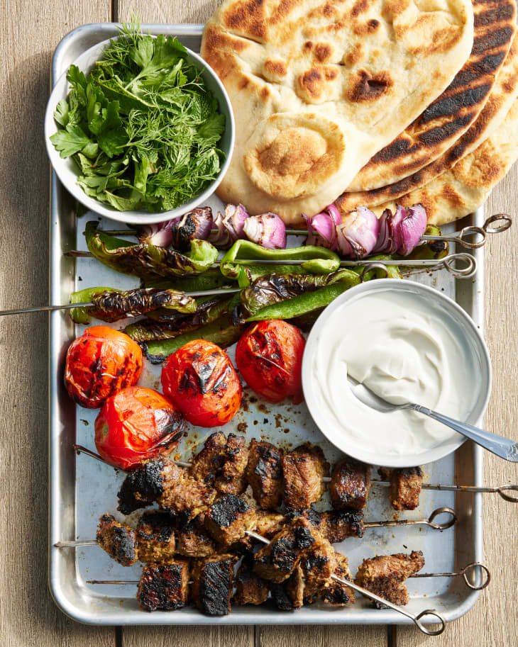 persian kebabs next to pita on a tray