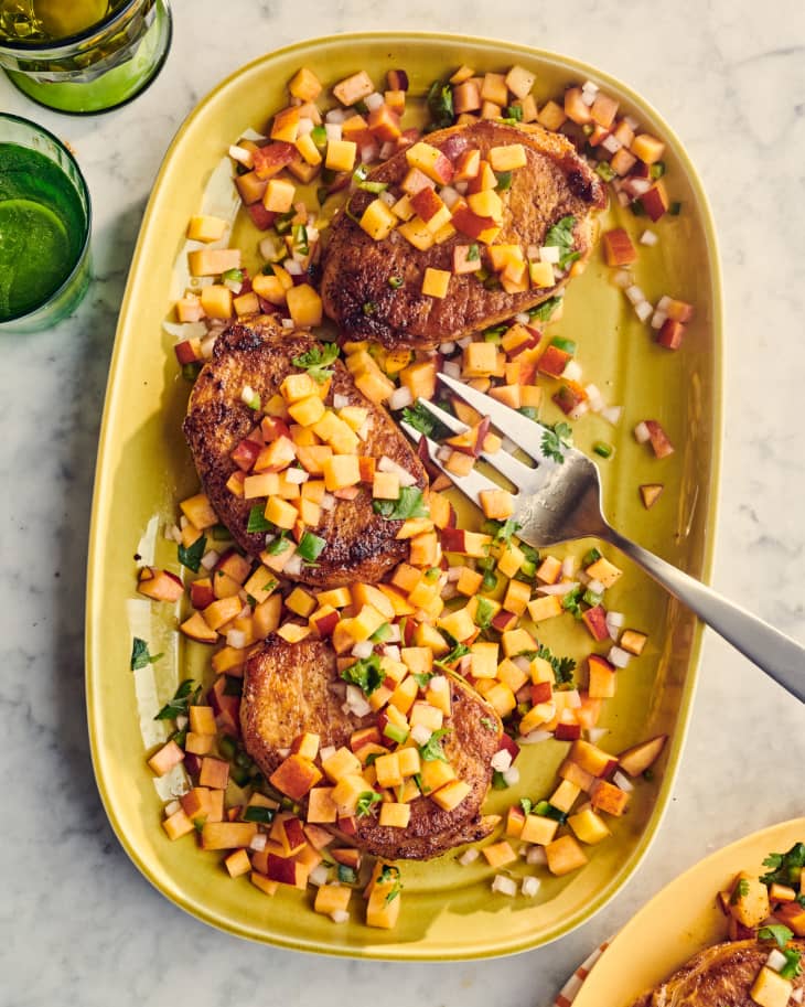 pork chops with peach salsa on a platter with a fork