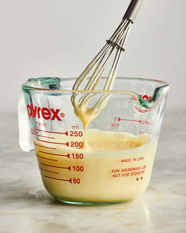 whisk dripping into a pyrex measuring glass