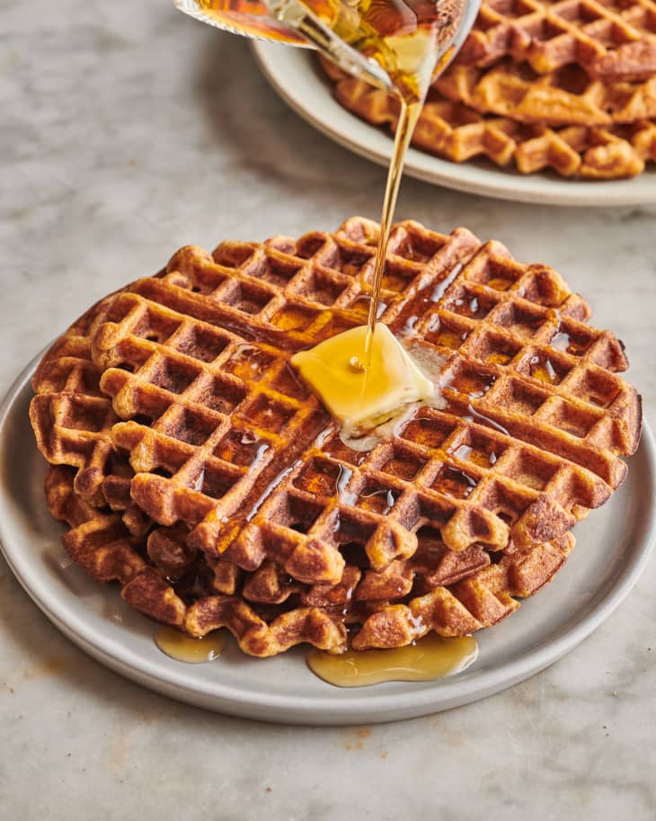 sweet potato waffles being drizzled with maple syrup