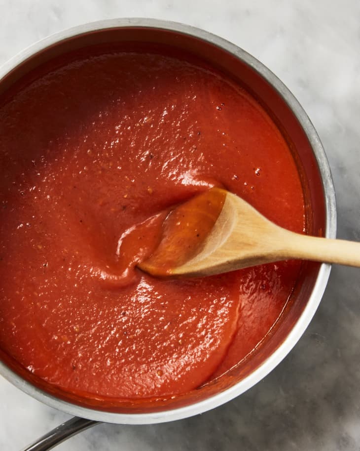 pomodoro sauce in saucepan being stirred with wooden spoon