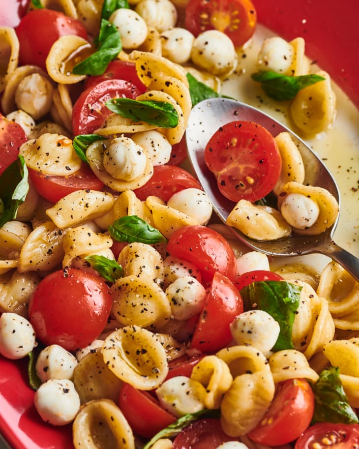 close up of caprese pasta salad in a red dish