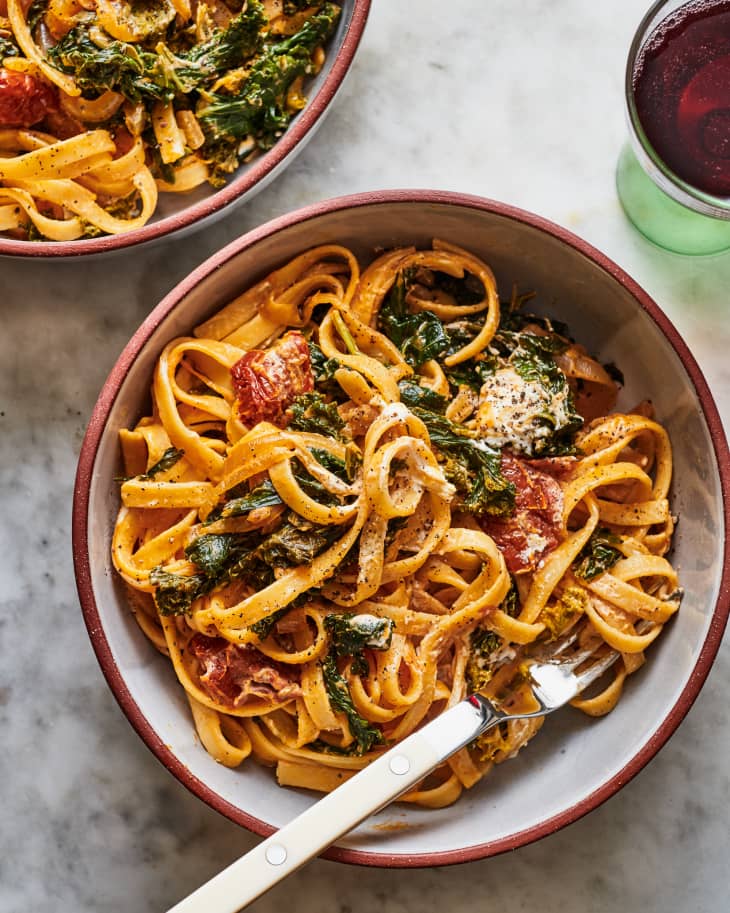 bowls of pasta with braised greens at the table