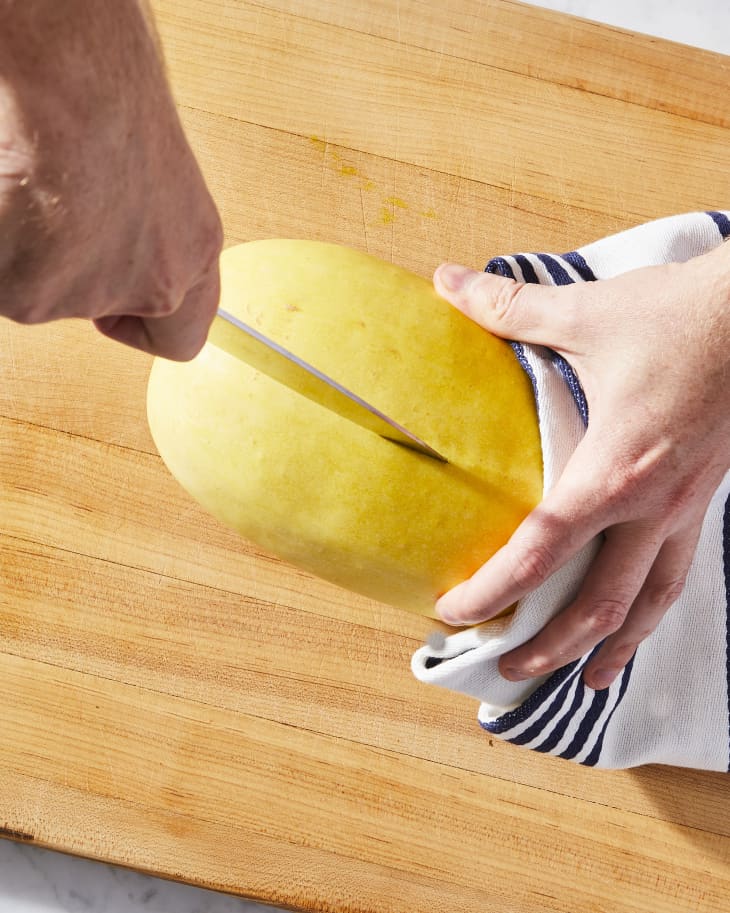 some slicing spaghetti squash with a towel in hand