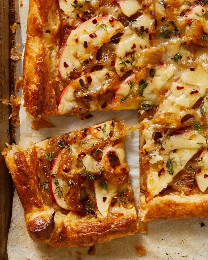 onion apple cheddar tart sliced on a baking sheet