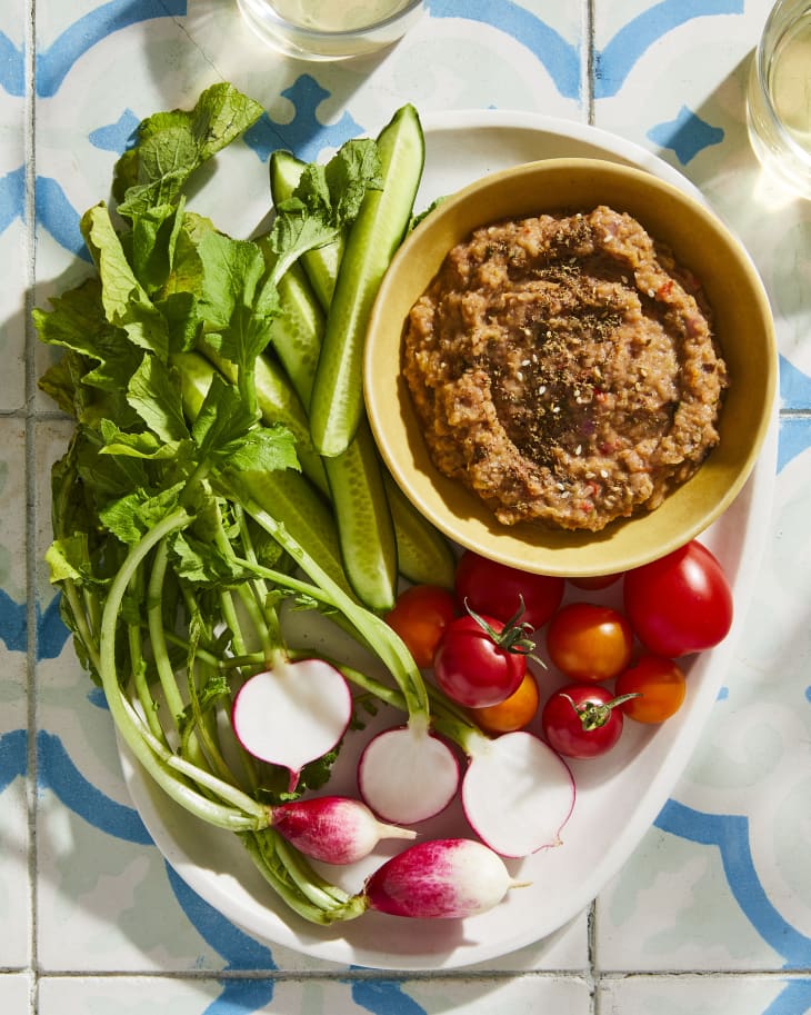 za'atar roasted veggie dip on serving platter surrounded by fresh vegetables.