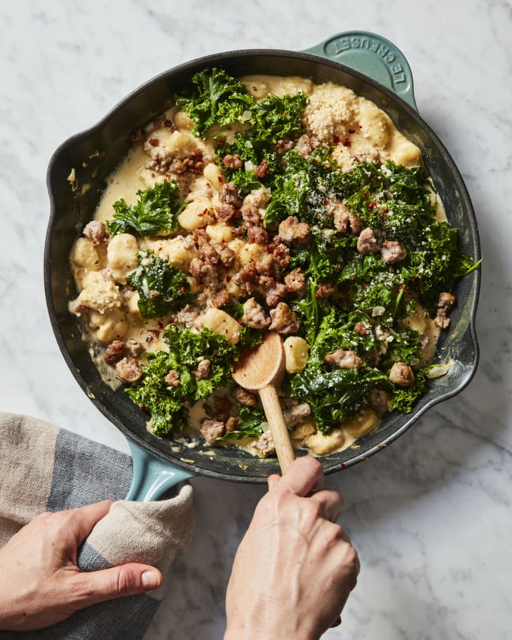 Overhead photo of 4 -ingredient creamy gnocchi with kale and sausage being stirred in a skillet