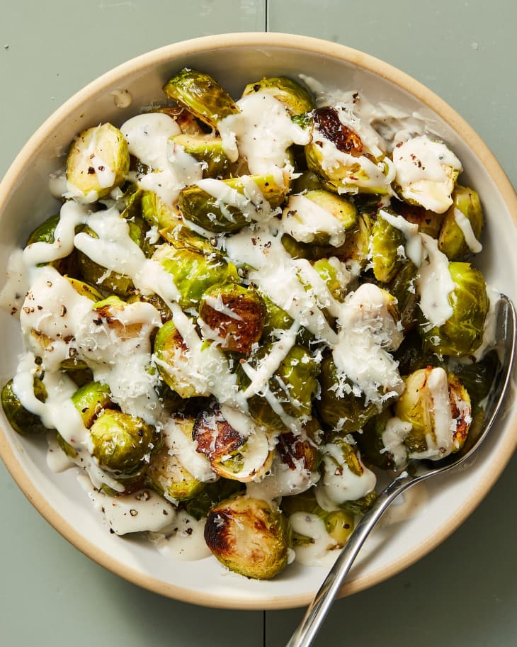 bowl of roasted brussels sprouts drizzled with cacio e pepe sauce