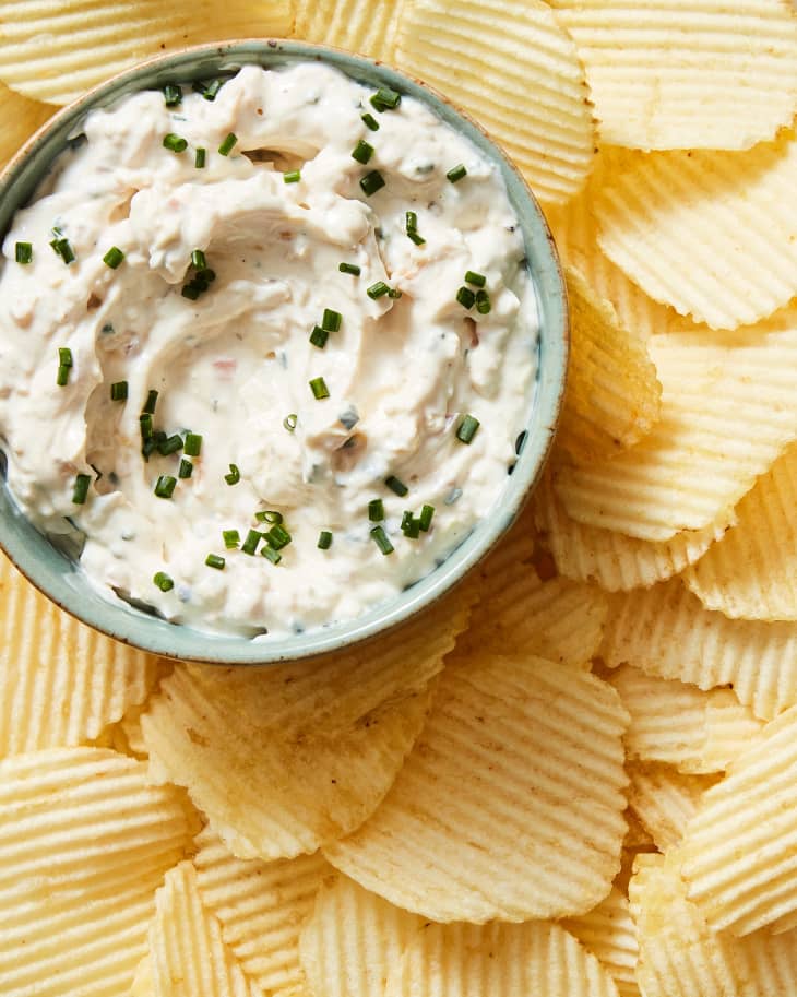 closeup of bowl of clam dip on platter with ridged potato chips
