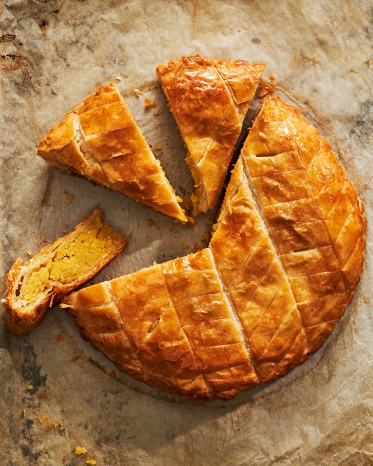 Overhead photo of sliced galette de rois. One slice is turned on its side to show the creamy almond filling inside