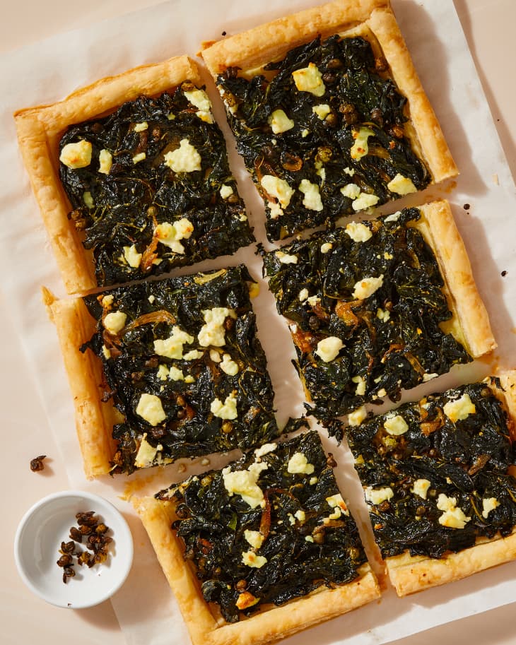 kale tart cut up on parchment with capers