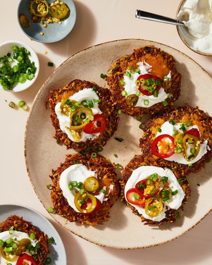loaded latkes on a plate with tomatoes and other fixings to top them