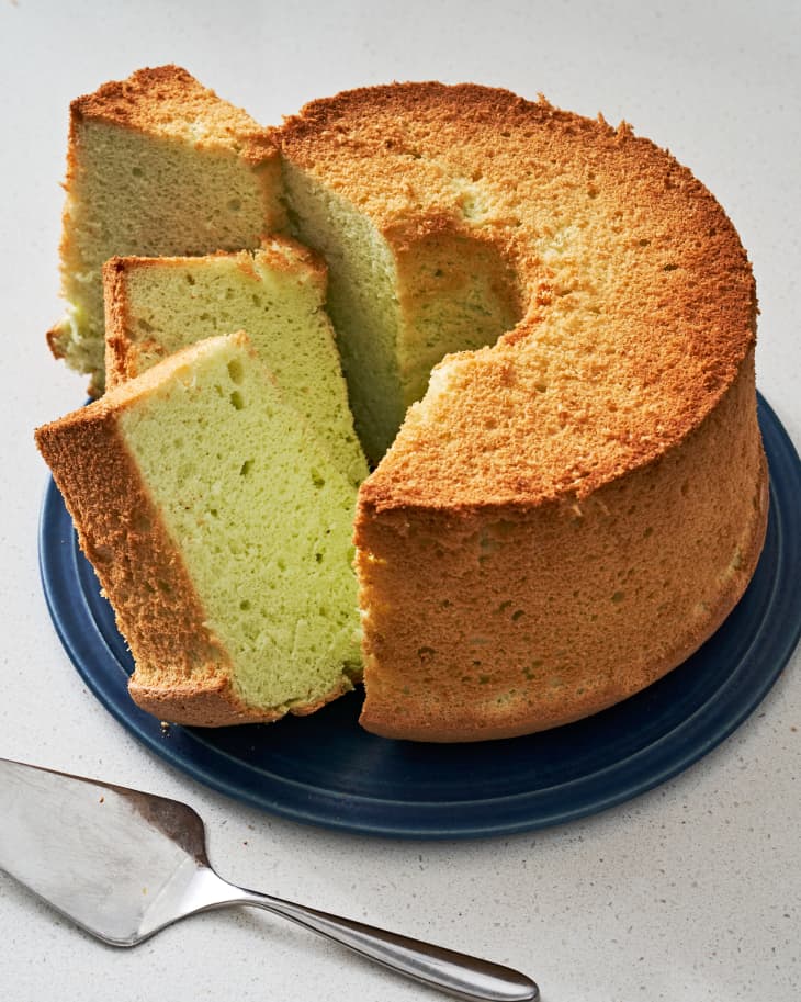 Photo of pandan cake on a plate with 3 slices cut out. Cake serving tool next to it