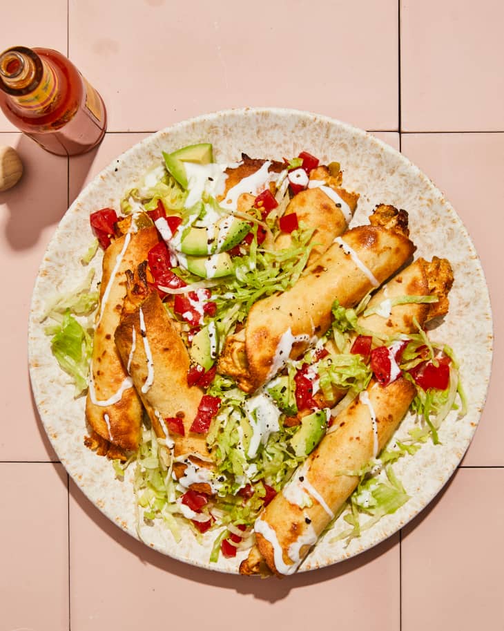 taquitos on a plate with someone taking one