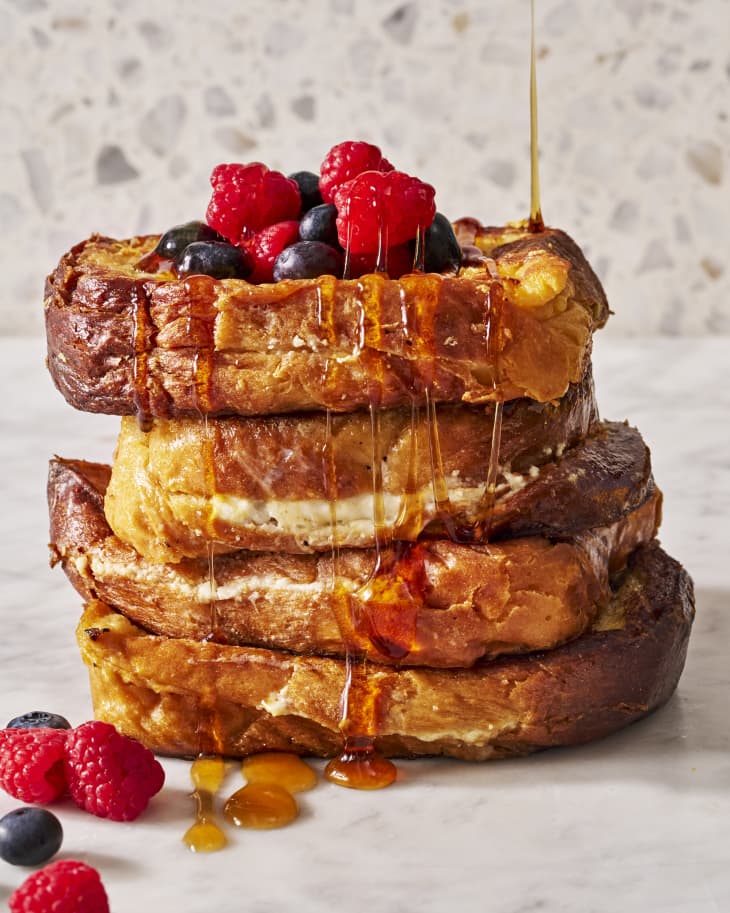 stack of stuffed French toast with berries having syrup drizzled