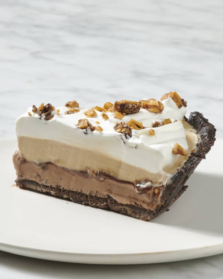 A slice of frozen mud pie on a white plate on a marble surface