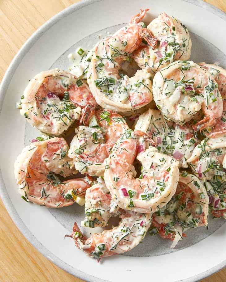 A plate of shrimp salad on a light wood surface