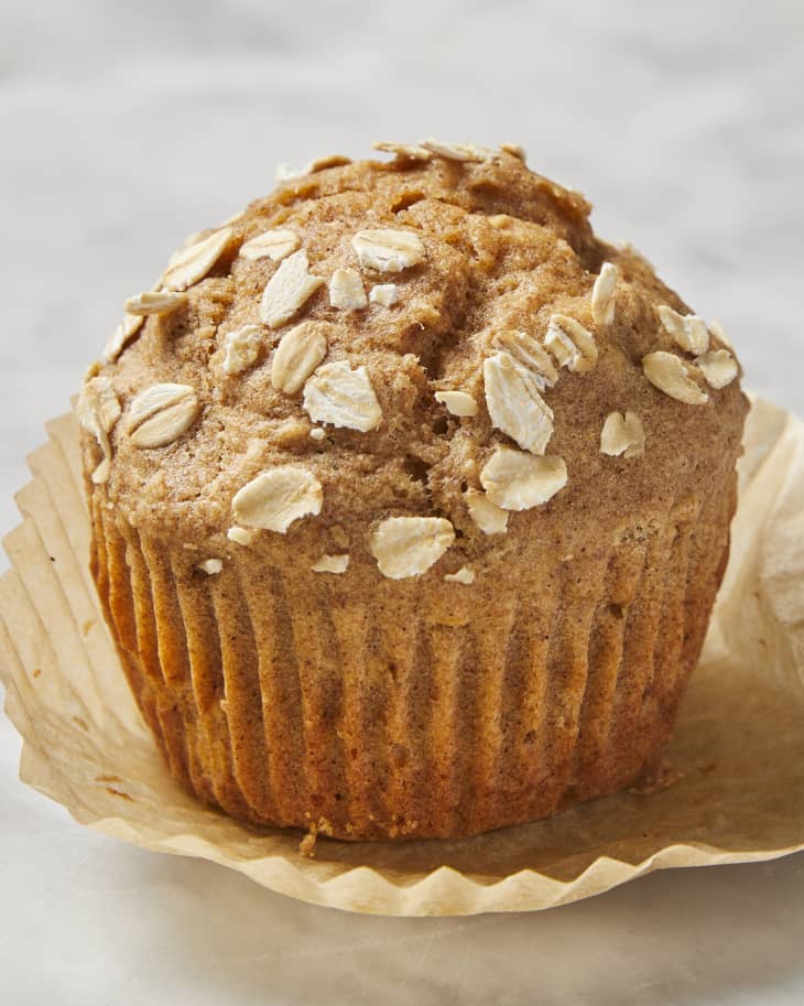 A close up of an applesauce muffin, unwrapped on a marble surface
