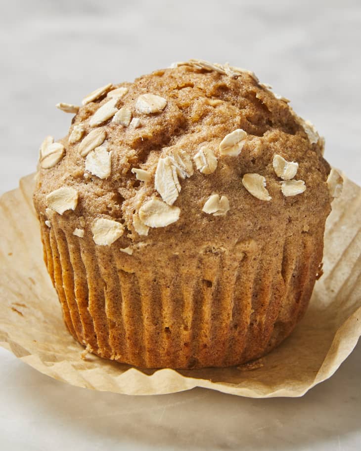 A close up of an applesauce muffin, unwrapped on a marble surface