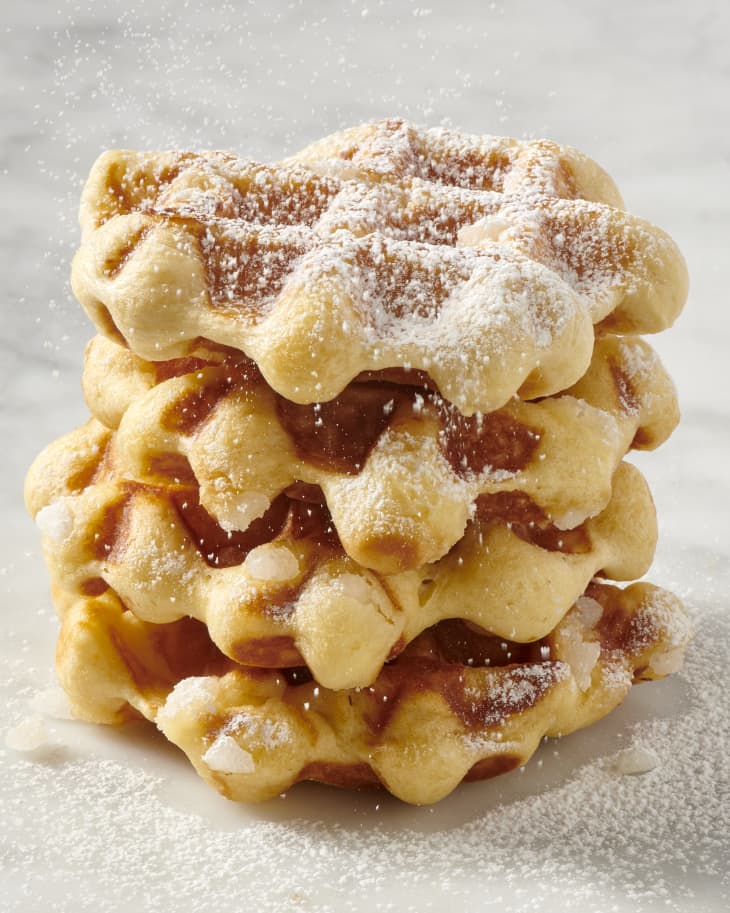 a stack of liege waffles topped with powdered sugar on a marble surface