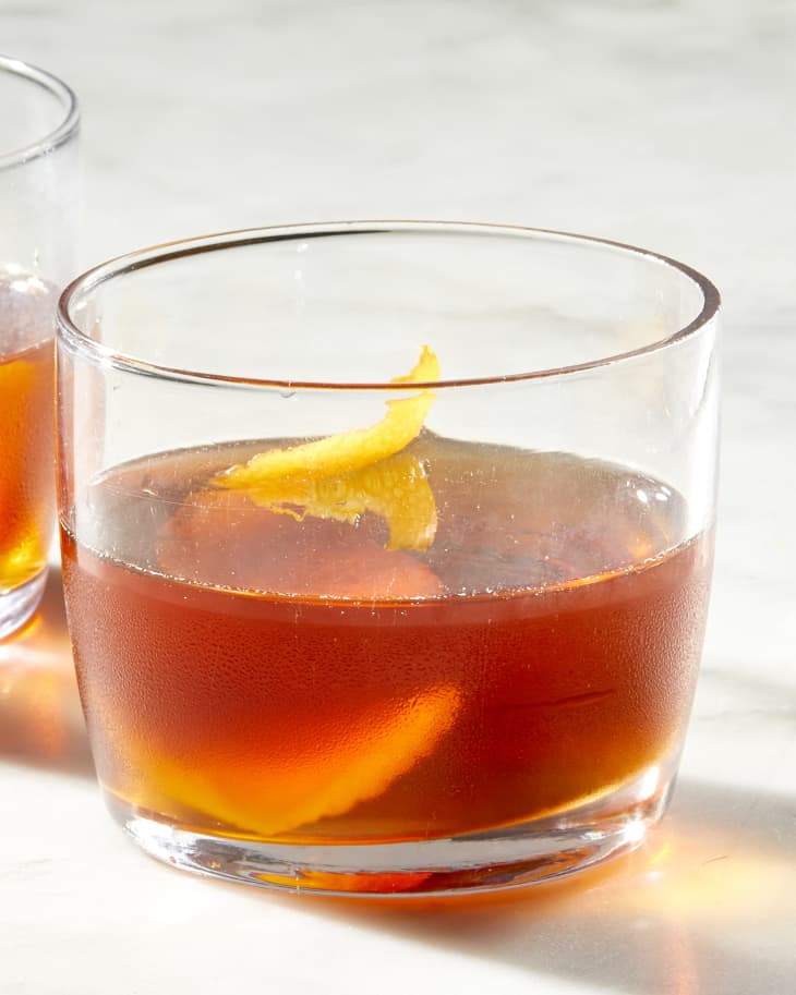 Close up view of the autumn sweater cocktail, on a marble surface with a citrus peel garnish in the drink.