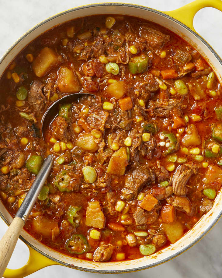 Overhead view of stew in a yellow pot with a ladle resting inside.