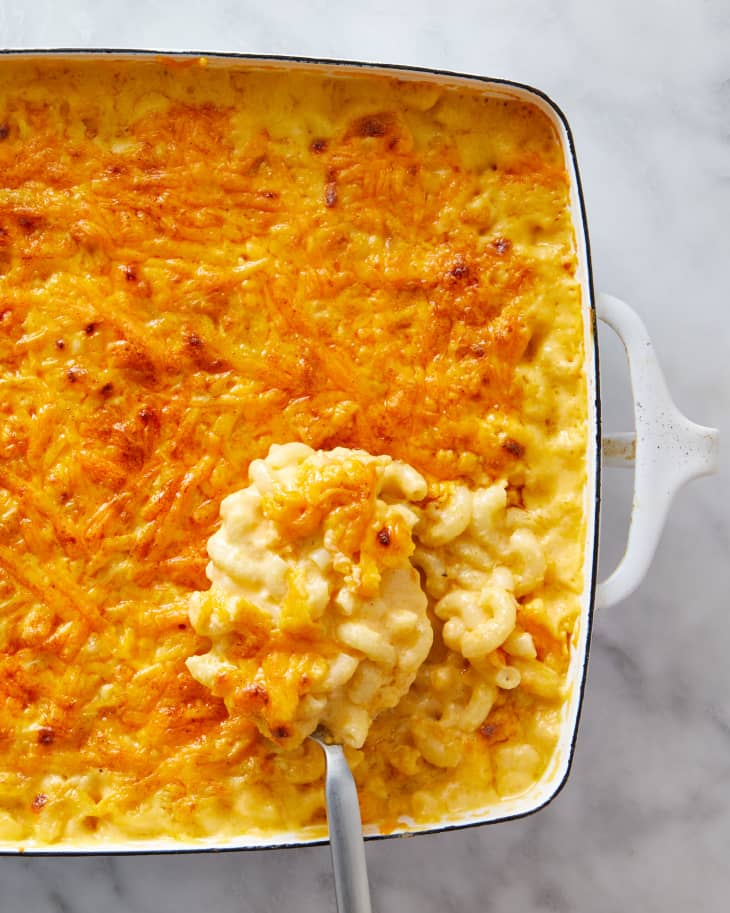A big scoop of baked mac and cheese being taken out of the baking dish.