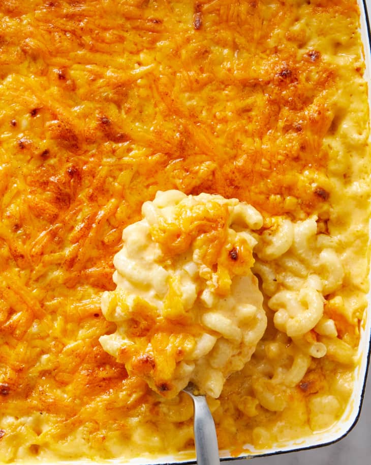 A big scoop of baked mac and cheese being taken out of the baking dish.
