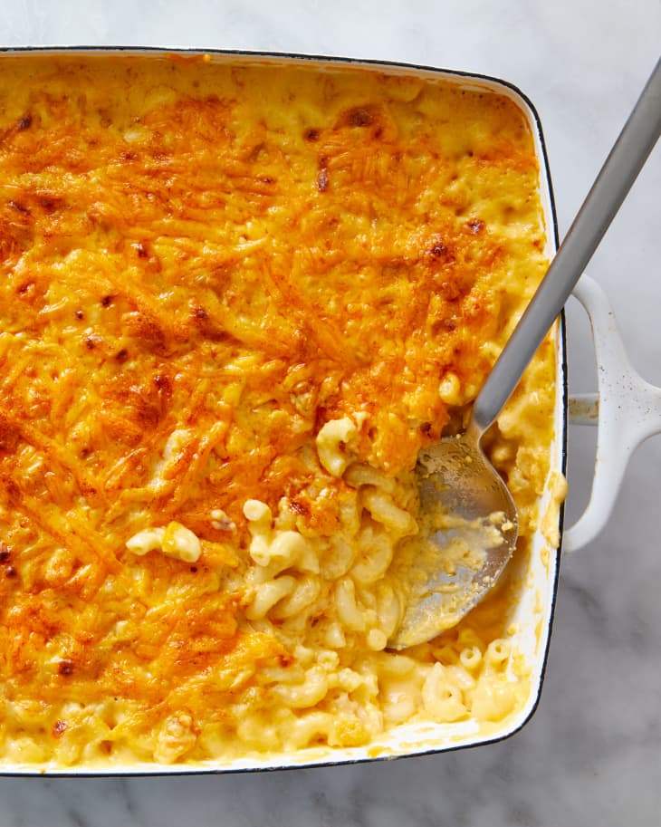 A large baking dish full of mac and cheese with a spoon inserted.