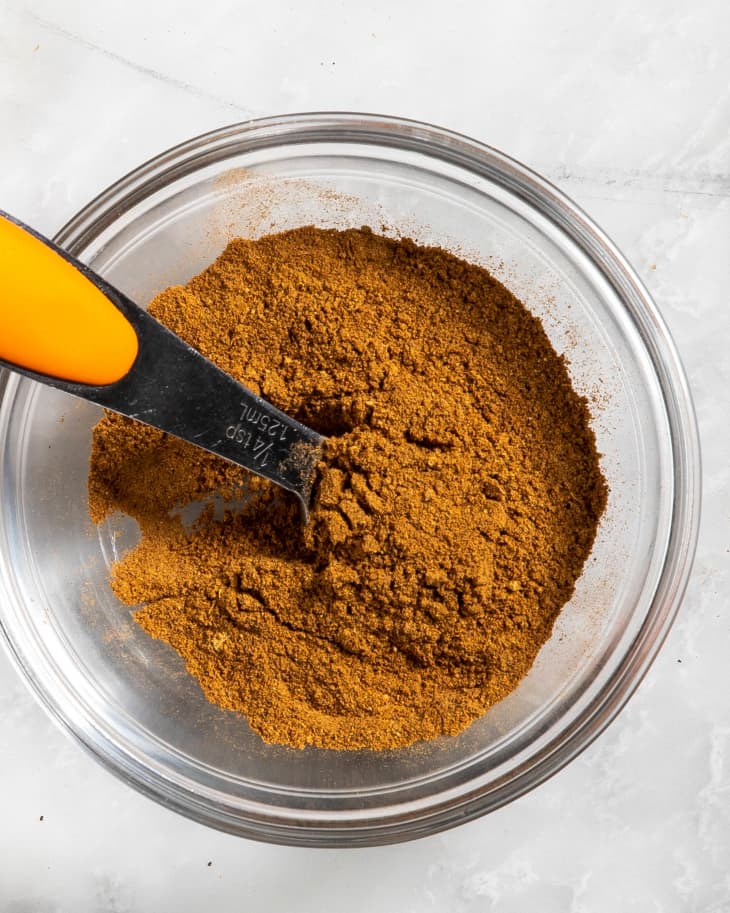 Overhead view of mixed spices in a clear glass bowl.