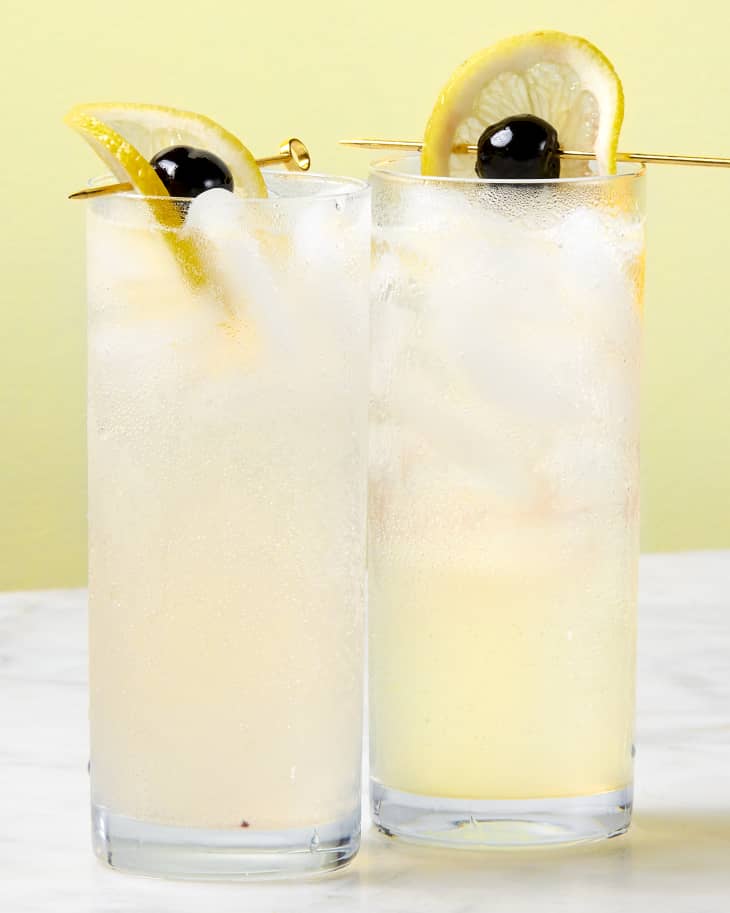 two clear high ball glasses garnished with skewered lemon and cherries.