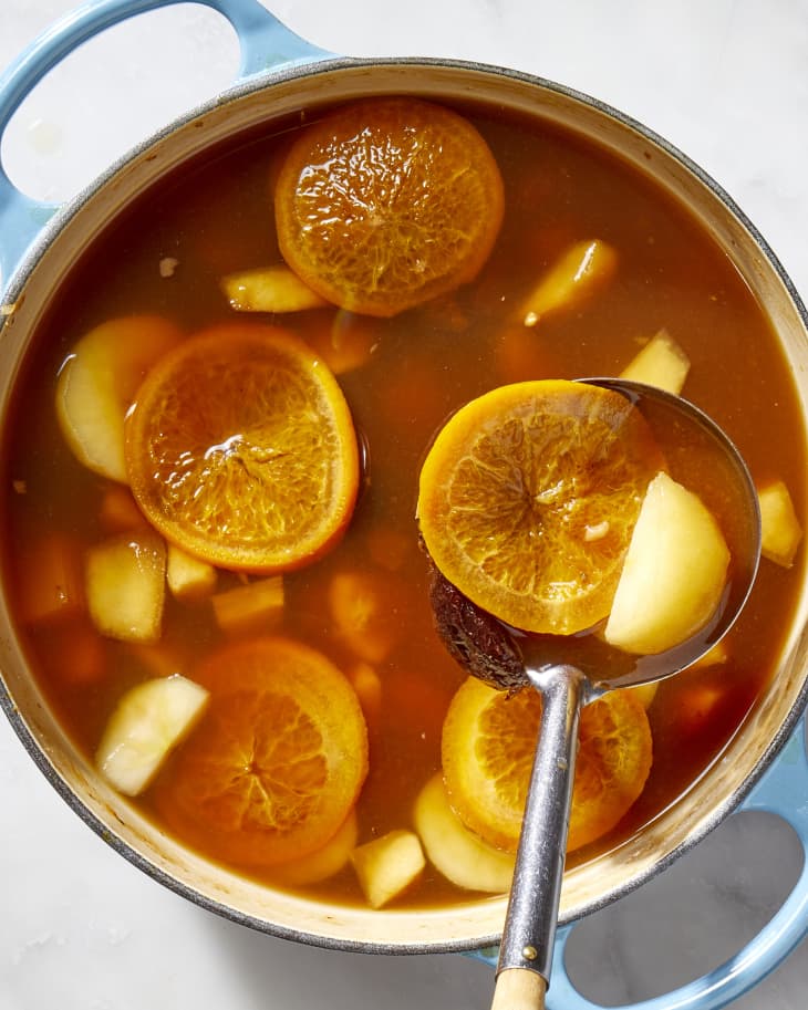 Overhead shot of punch in a blue pot, with oranges and apples floating on top.