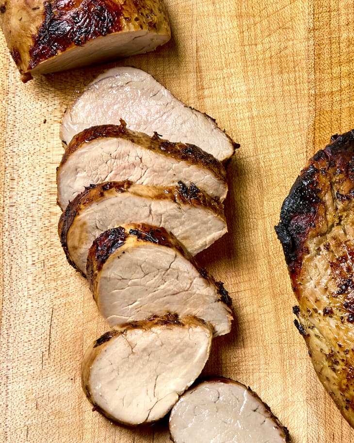 Overhead shot of a partially sliced mojo pork tenderloin on a wooden cutting board.