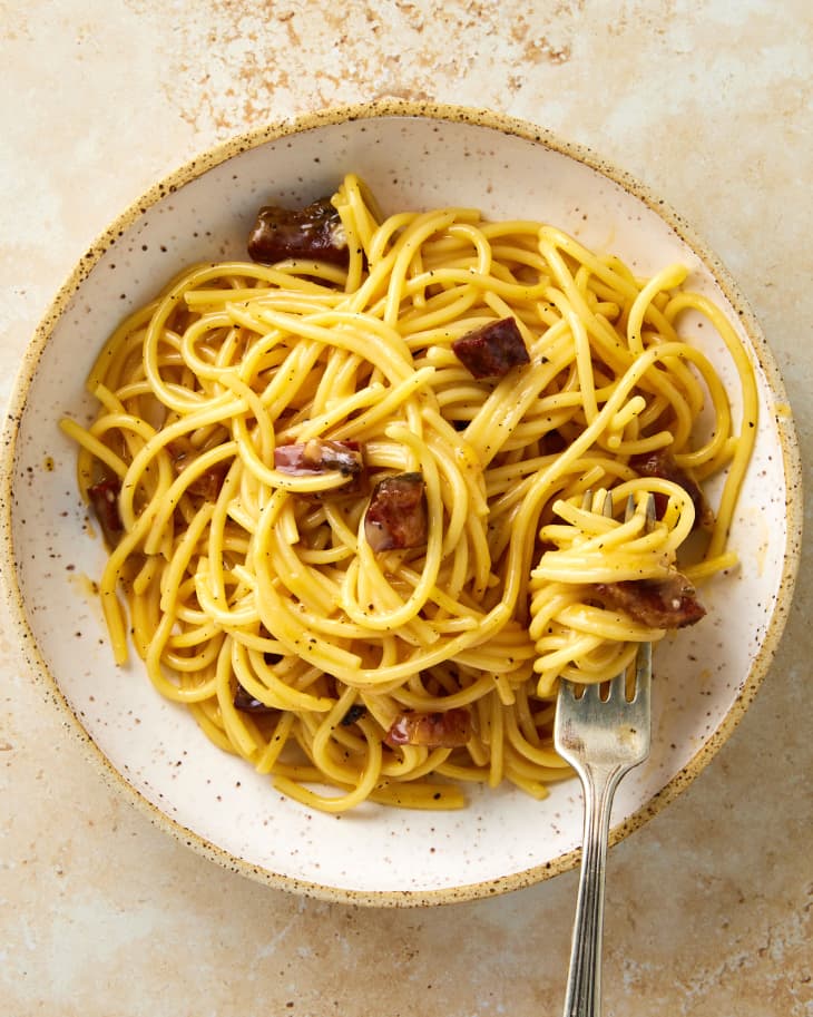 Overhead shot of carbonara in a bowl with a fork resting in the bottom right of the bowl.